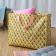 Yellow jumbo storage bag with a pink floral pattern and pink handles.