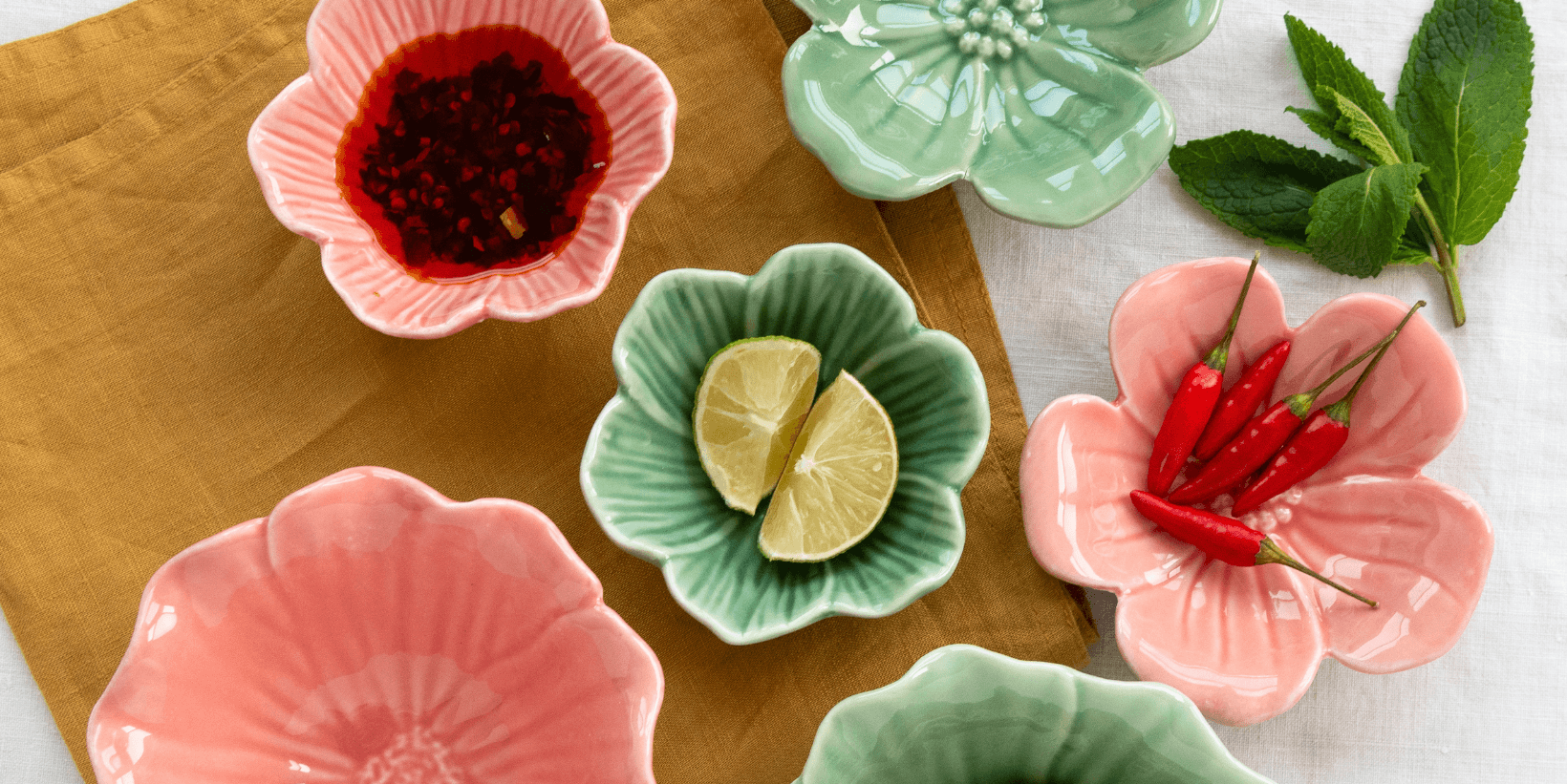 Several green and pink ceramic bowls shaped like open flowers lie on a table