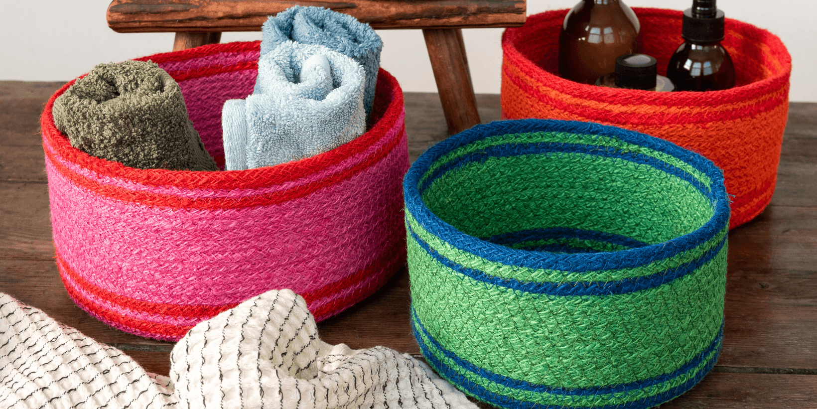 Brightly coloured basket sit on a wooden surface, filled with flannels and bottles