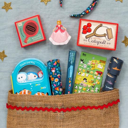 An array of stocking filler toys and games is spread out on a blue cloth