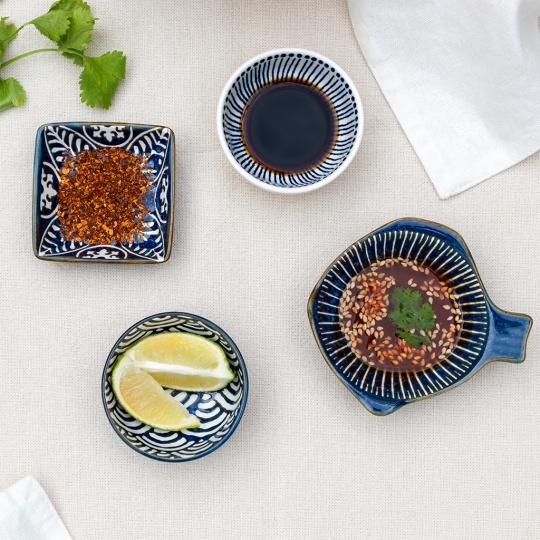 Ceramic dipping bowls shown with soy sauce, chilli flakes and lime wedges.