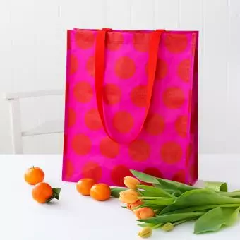 Recycled plastic shopping bag red circles pink background