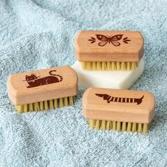 three Wooden nail brush with engraved designs of a butterfly, a cat, and a sausage dog