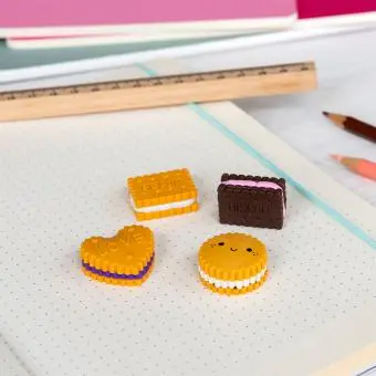 Four biscuit-shaped erasers in different styles and colours, placed on a notebook 