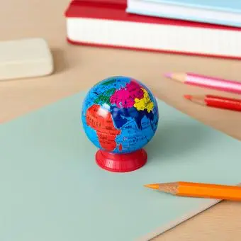 Colourful globe sharpener with a red base placed on a notebook 