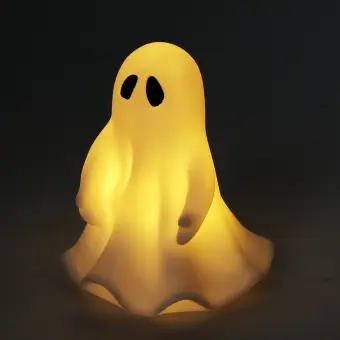 White ghost night light with black eyes, with its light turned on