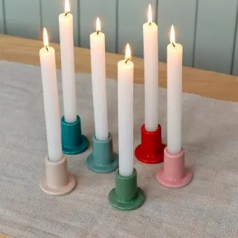 mixed ceramic candle holder with a cylindrical shape and a wide, flat base, holding a lit candle