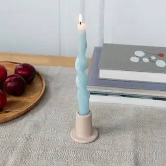 Taupe ceramic candle holder with a cylindrical shape and wide flat base, holding a lit candle