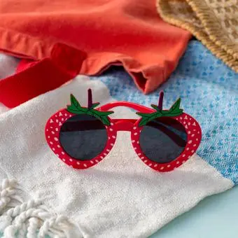 Red strawberry-shaped funglasses with green leaves, and dark round lenses