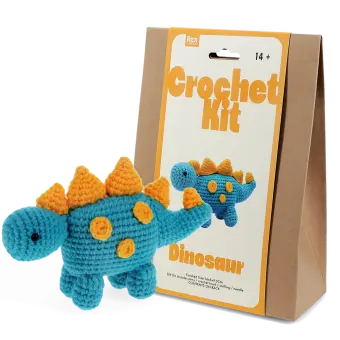 Blue crocheted dinosaur placed next to its packaging