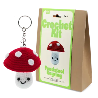 Crochet kit packaging displayed next to a finished red and white toadstool mushroom keychain