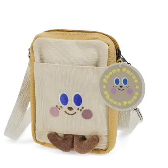 Beige and yellow crossbody bag with a front pocket featuring a smiling face design and two small brown plush feet at the bottom.