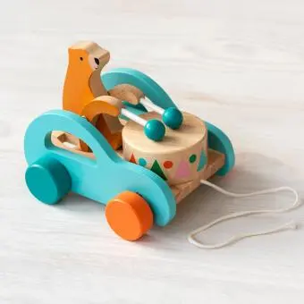 Wooden pull-along toy featuring a bear playing a drum, with colorful wheels
