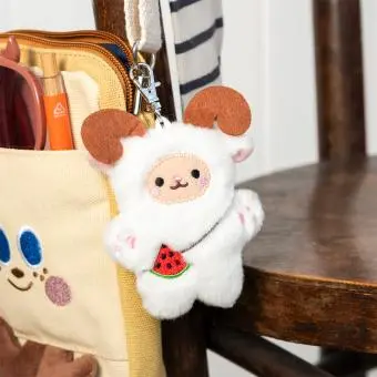 Yeti-shaped plush keyring with pink ears and paws, a watermelon accessory with metal clasp