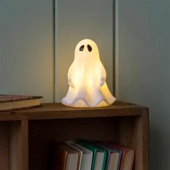 White ghost night light with black eyes, with its light turned on