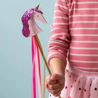 Kid holding pink unicorn wand with glittery top and ribbon streamers