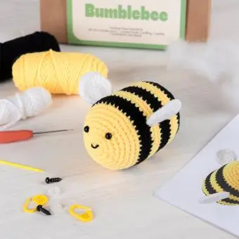 Crochet kit packaging and finished crocheted bee beside it