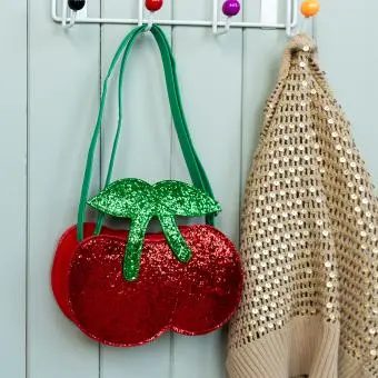 Children’s glitter handbag shaped like a red cherry, with green leaves and a green strap