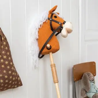 hobby horse toy with white mane and black bridle on a wooden stick