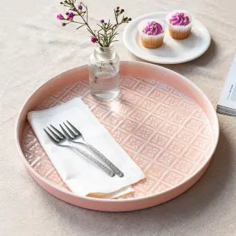 Round enamel trinket tray in soft pink displayed with fork and flower vase