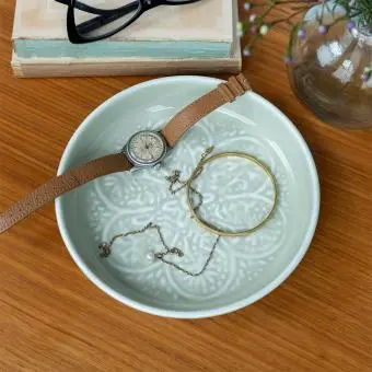 enamel trinket dish in light grey displayed with a watch and jewellery