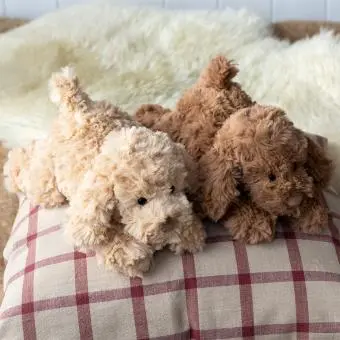 Two plush dog toy lying down with floppy ears and soft fur