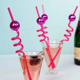 Four pink curly straws each topped with a small pink disco ball decoration.