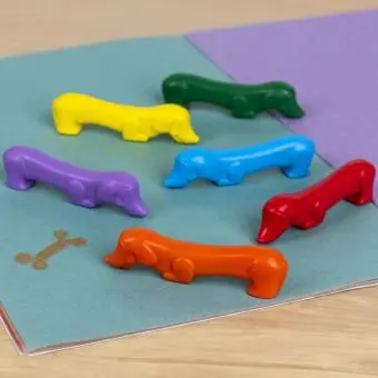 Set of six sausage dog-shaped crayons in yellow, purple, red, blue, green, and orange.