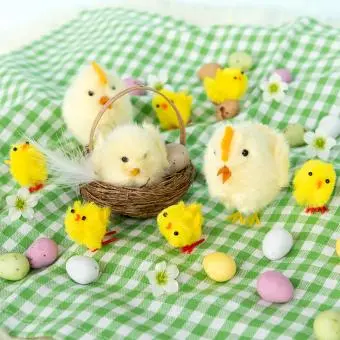 Fluffy chicks and eggs arranged on a green gingham cloth.