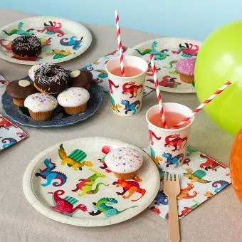 Dinosaur-themed party plate displayes with matching napkins and a cup.