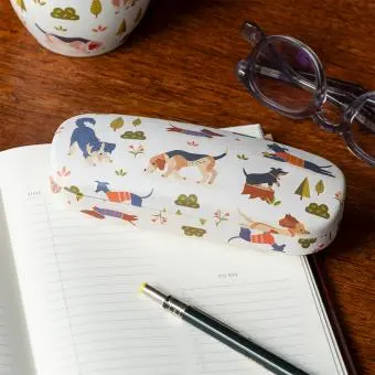 glasses case with playful dog illustrations resting on a notebook beside a pair of glasses.