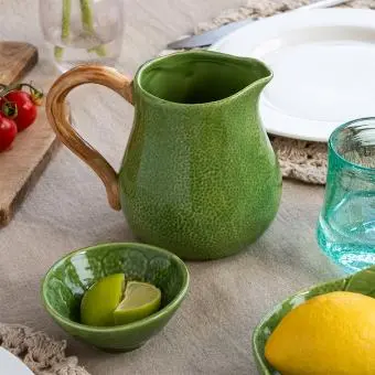 Green ceramic jug with textured surface and a curved brown handle