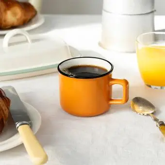 Espresso mug in orange showing with black coffee.