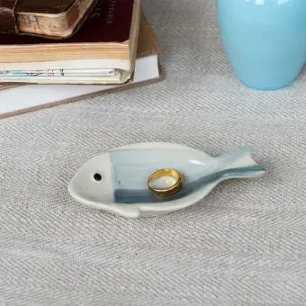 Blue and white ceramic fish‑shaped trinket dish displayed with ring.
