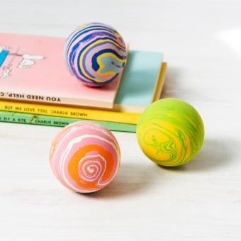 Three colourful bouncy balls in pink, purple and green with swirling patterns.