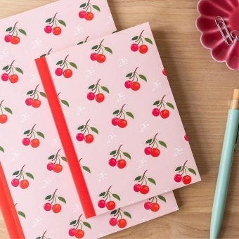 Pink notebook with cherry design on the cover.