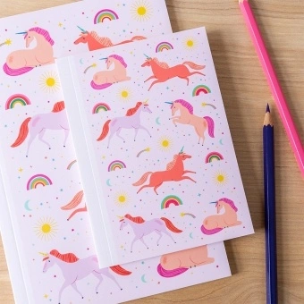 Pink notebook with colourful unicorns, rainbows, stars, and suns on the cover.