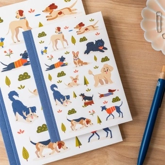 Notebook with illustrated dogs in a park scene on the cover.