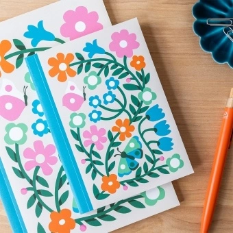 Notebook with colourful illustrated flowers, leaves, and butterflies on the cover.