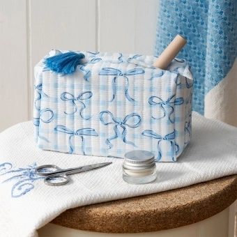Light blue quilted makeup bag with a bow pattern and tassel.