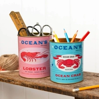 Two Ocean’s Brand storage tins featuring lobster and crab illustrations in pink and blue.
