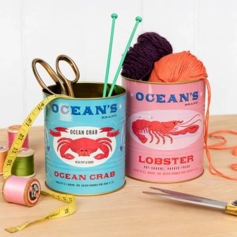 Two Ocean’s Brand storage tins featuring lobster and crab illustrations in pink and blue.