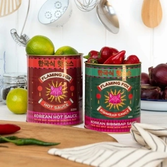 Two Flaming Fox Korean sauce storage tins, one red hot sauce and one green bibimbap design