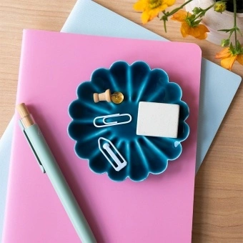 Blue enamel flower-shaped trinket dish holding clips and small items