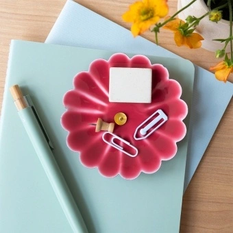Red enamel flower-shaped trinket dish holding clips and small items