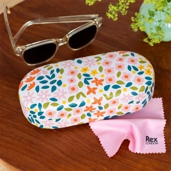 Ditsy floral-patterned sunglasses case with cleaning cloth on a wooden table.