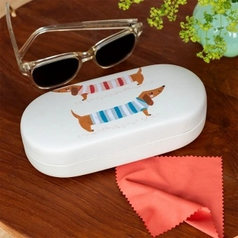 Sausage dog-patterned sunglasses case with cleaning cloth on a wooden table.