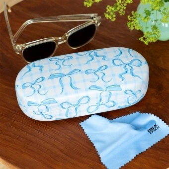 Blue bow-patterned sunglasses case with cleaning cloth on a wooden table.