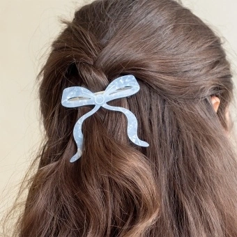 Hair clip featuring a pretty bow design in blue, with hints of marbling and translucence. 