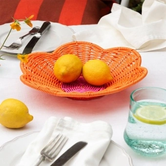 A shallow orange woven plastic basket with a flower-shaped rim and a pink centre.